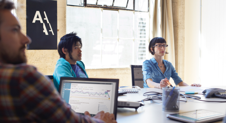 Three coworkers sit around a conference table