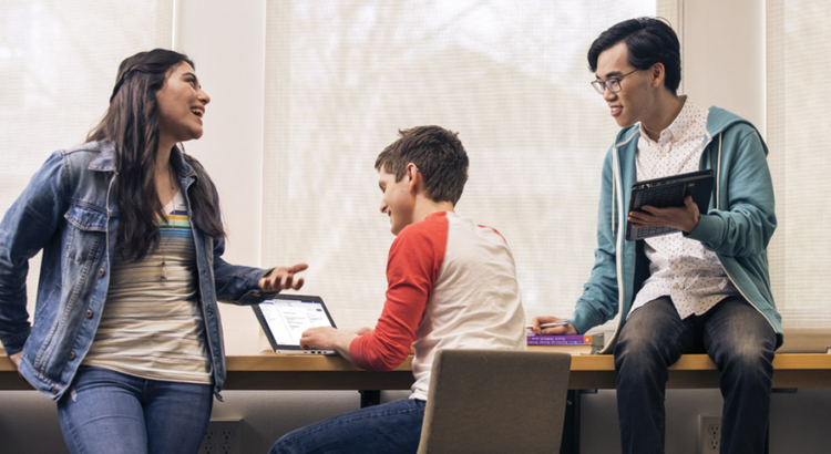 Three students gather at a windowside counter