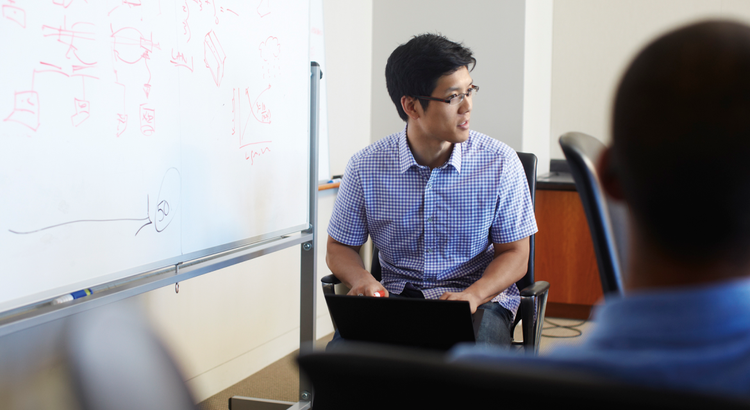 A man in a checkered shirt sits with a laptop