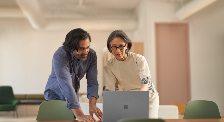 Two colleagues stand at a long table in a bright, modern office