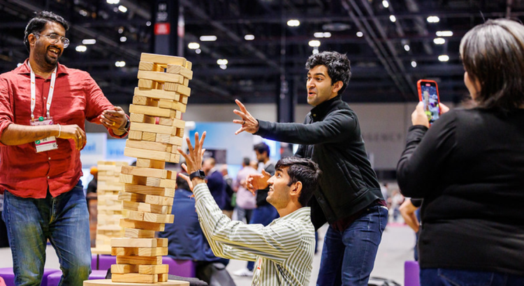 A group of people at an event play a giant wooden block stacking game
