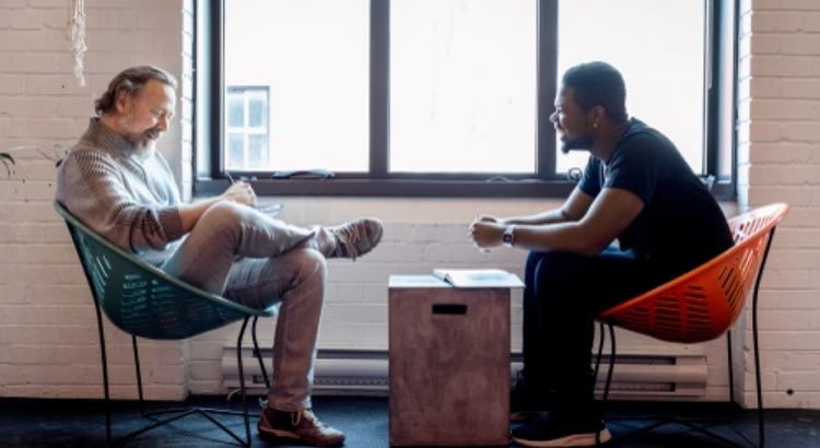 Two people sit facing each other in modern lounge chairs