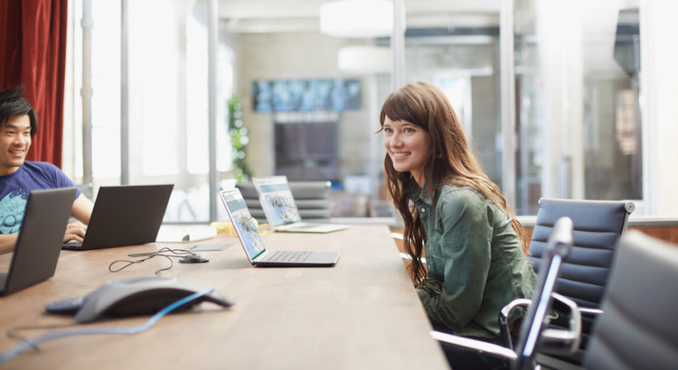 Two people work at a long conference table