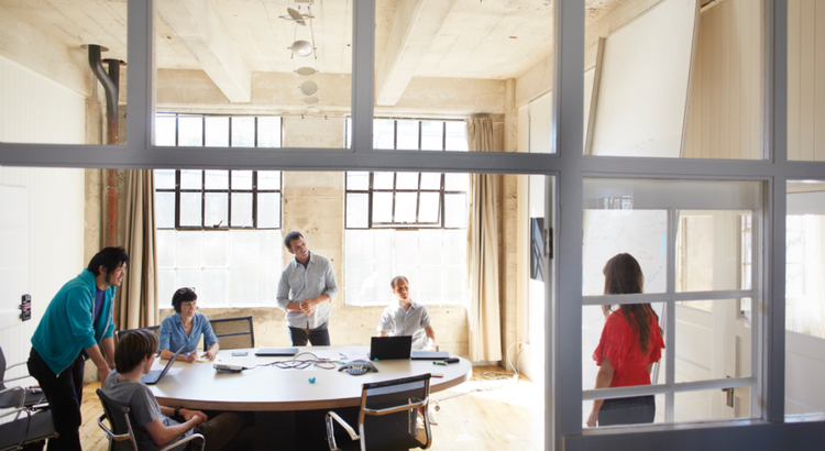 A group of people are gathered in a bright, industrial-style meeting room