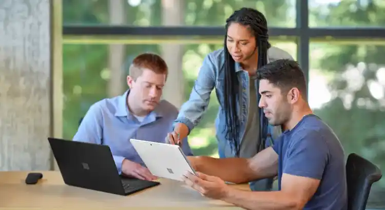 Three colleagues sit around a table in a bright office