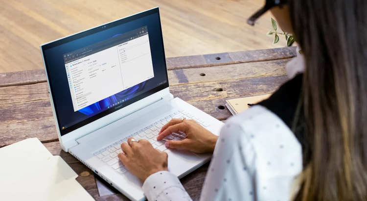 Person working on a white laptop at a rustic wooden table
