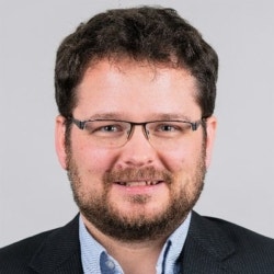 a man wearing glasses and smiling at the camera