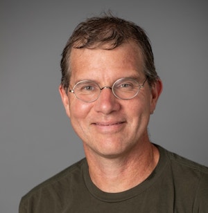 A man wearing glasses and smiling
