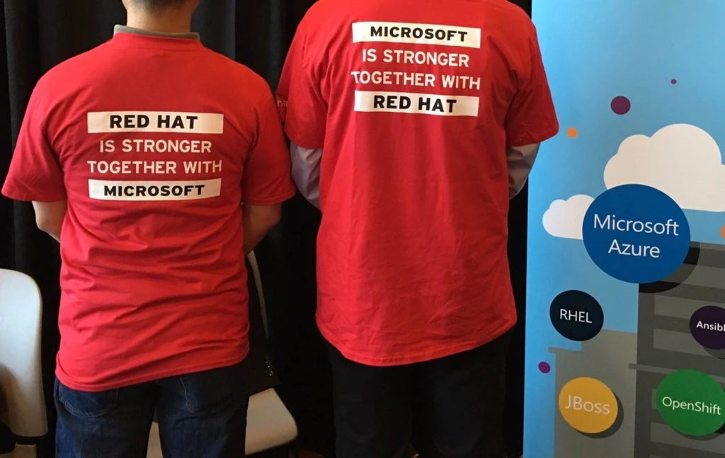 the backs of two people wearing red t-shirts that read "Red Hat is Stronger Together with Microsoft"