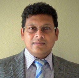 a man wearing a suit and tie smiling at the camera