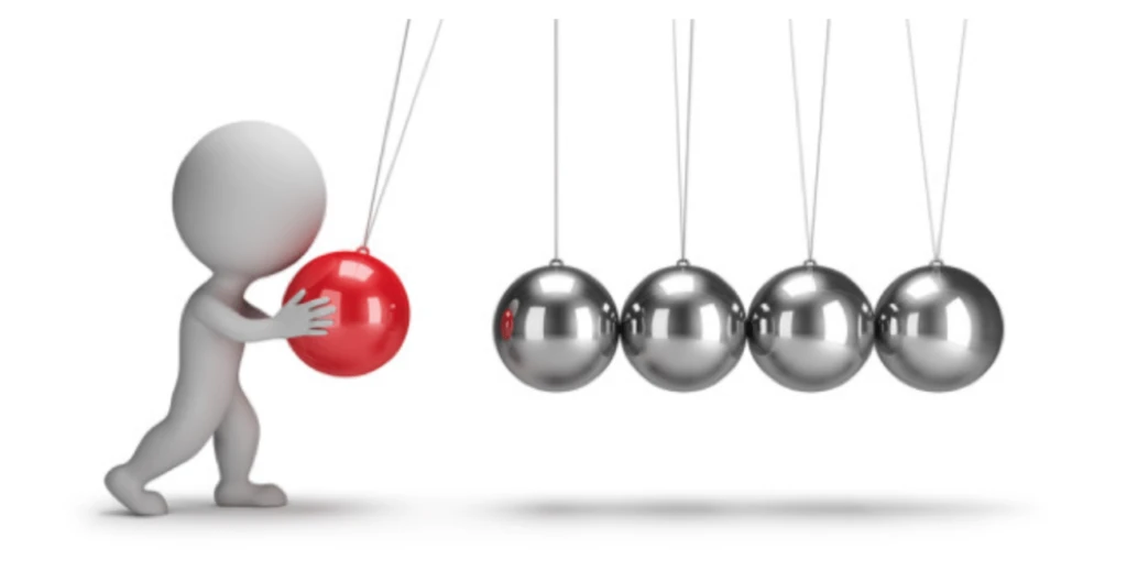 An image of pendulum balls with a person dragging one red ball backward.