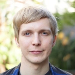 a man wearing a blue shirt and smiling at the camera