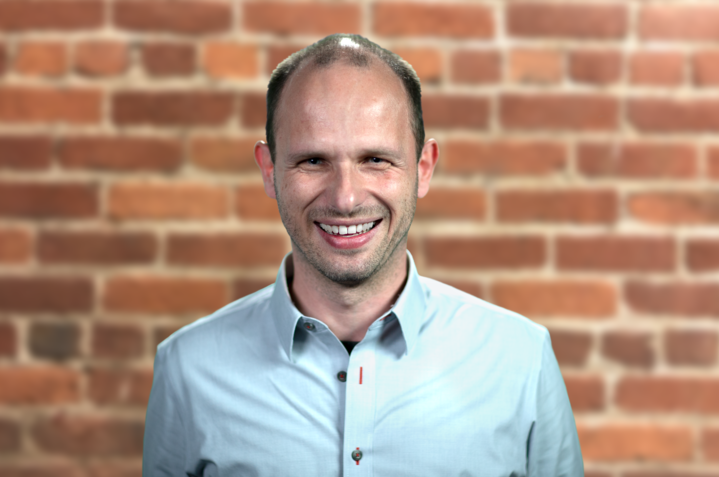 a man standing in front of a brick wall