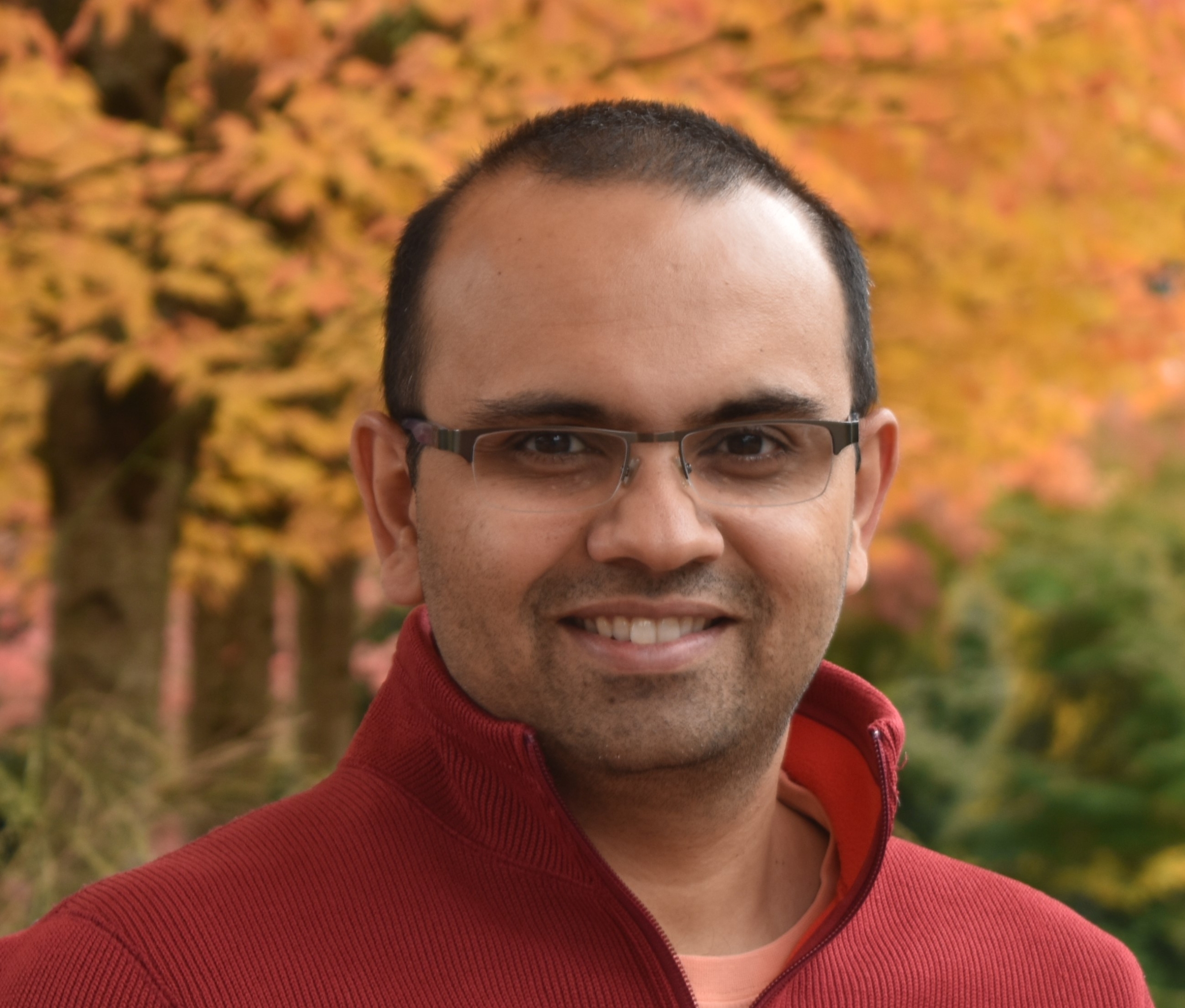 a man wearing glasses smiling at the camera