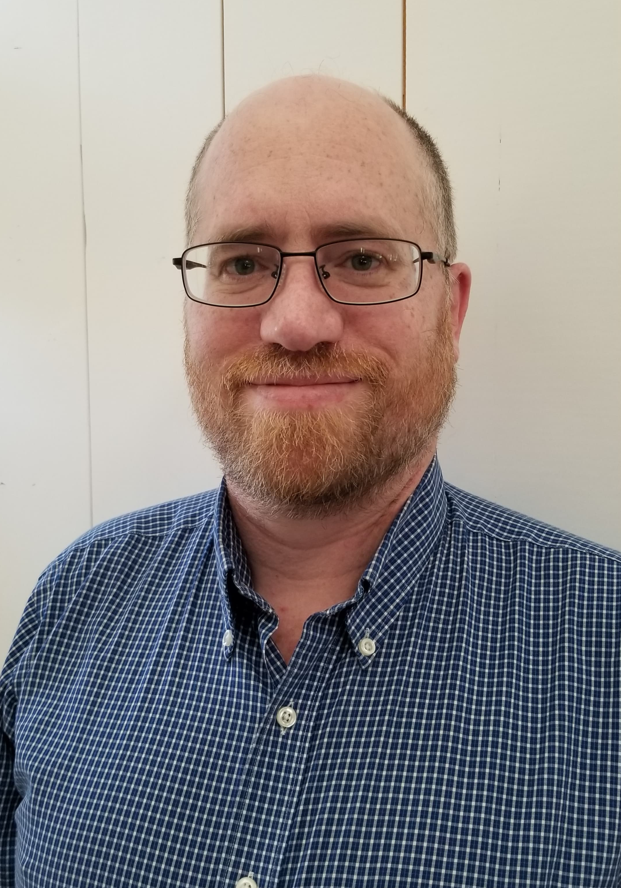 A man wearing glasses and smiling at the camera.