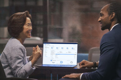 A man and woman sitting at a table with a laptop