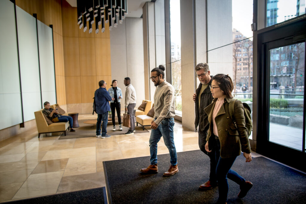 Office lobby with natural light and a modern décor, a group of developers are walking and chatting.